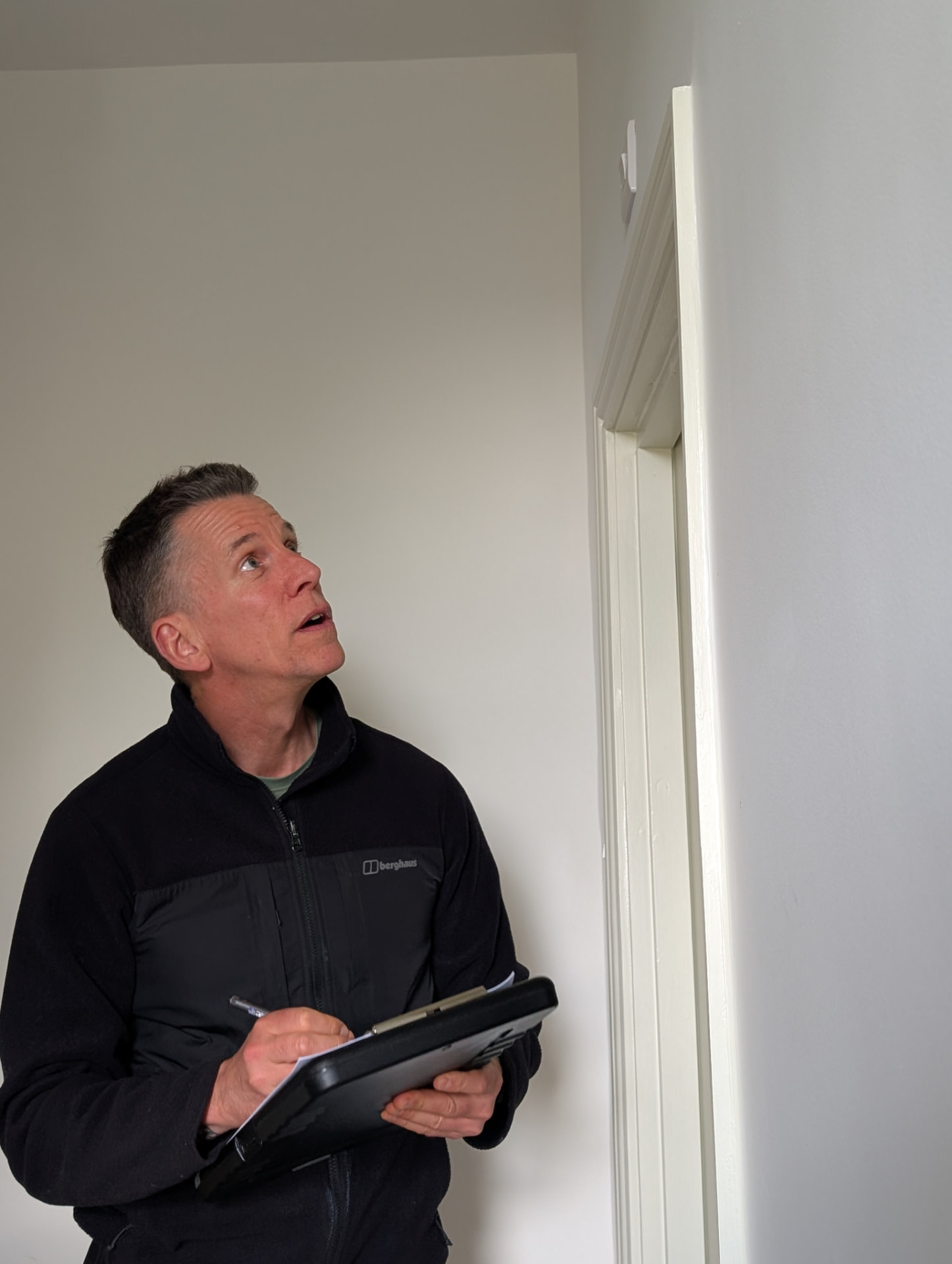 Nev inspecting a property room by room with a clipboard